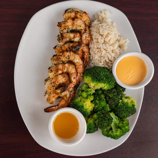 Grilled shrimp, rice, and broccoli with two dipping sauces on a white plate.